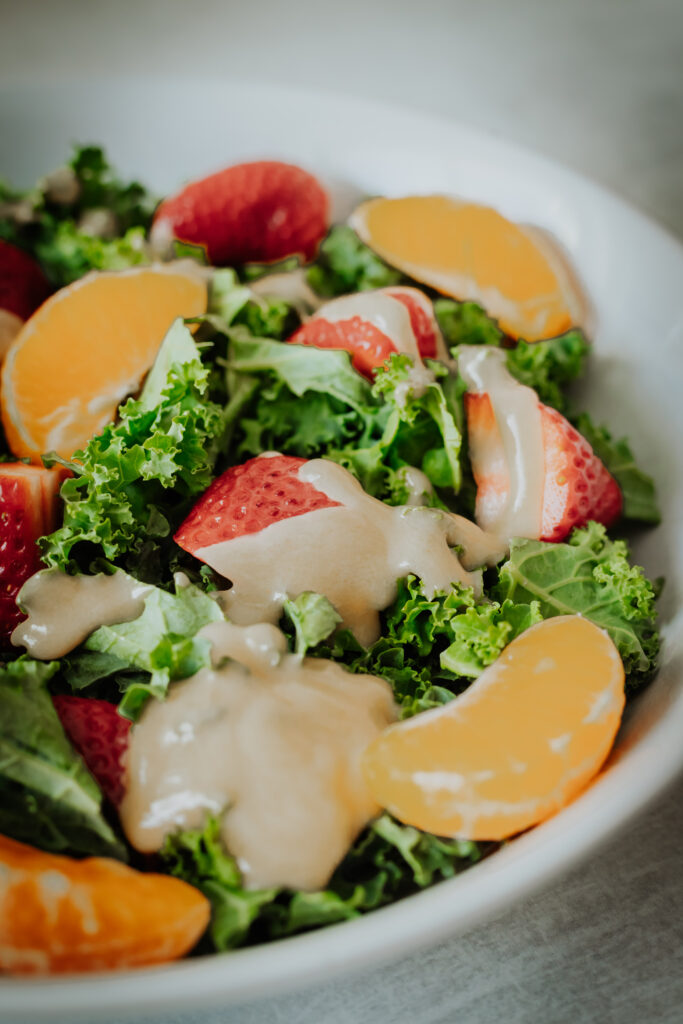 kale fruit salad with red onions, pumpkin seeds and tahini dressing
