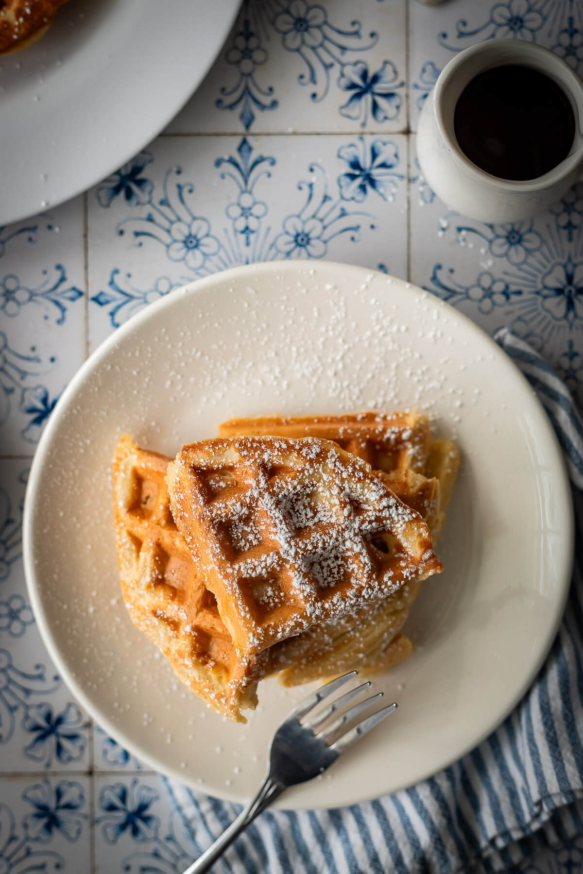 gluten free waffles with powdered sugar syrup and butter on a plate