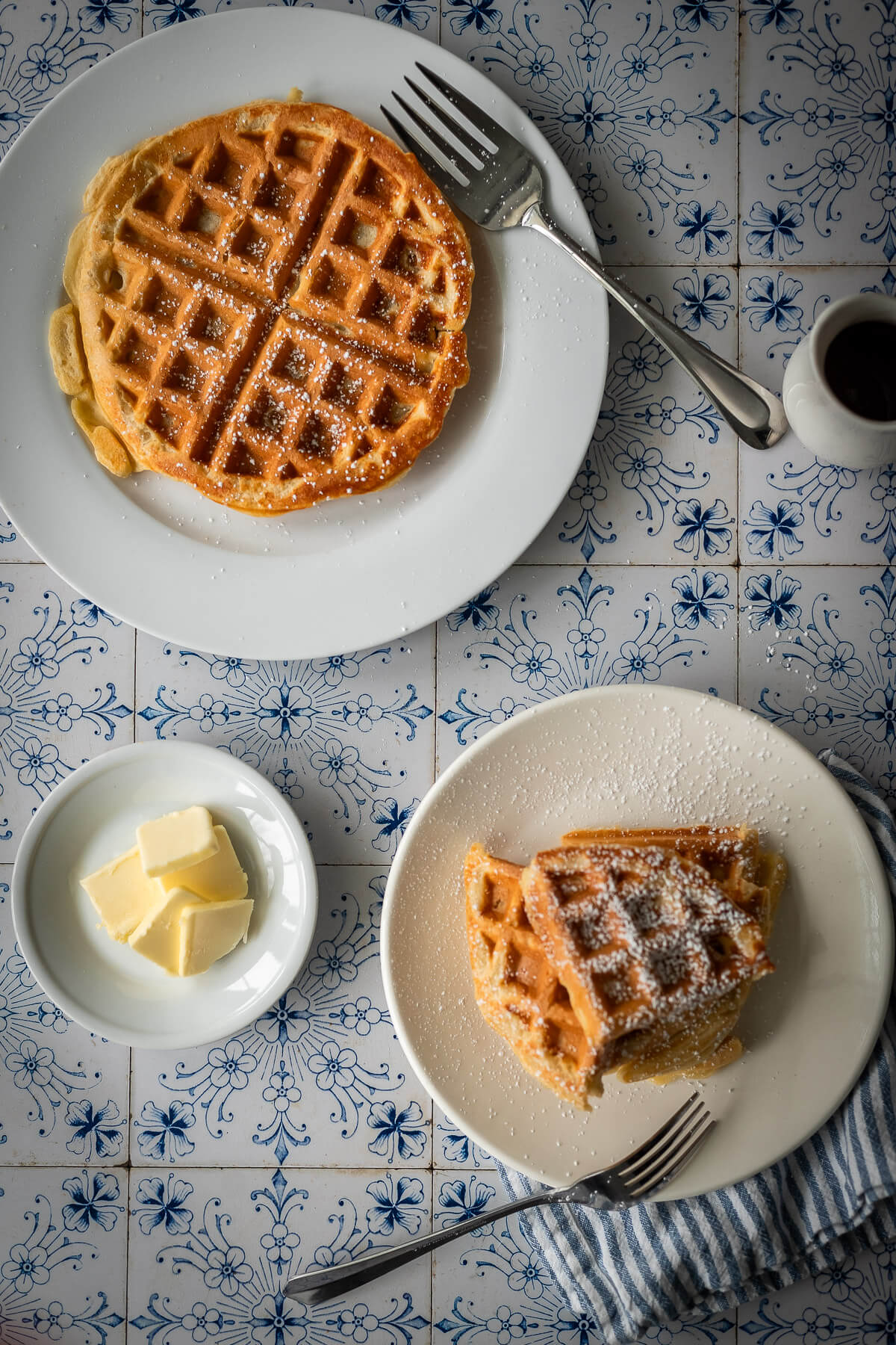 gluten free waffles with powdered sugar syrup and butter on a plate