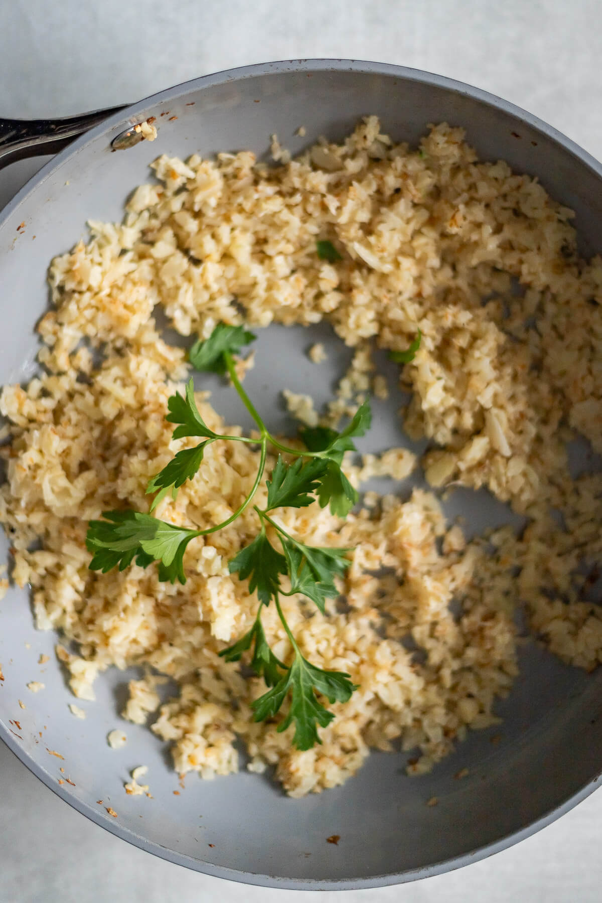 Brown Butter Cauliflower Rice with parsley in a skillet