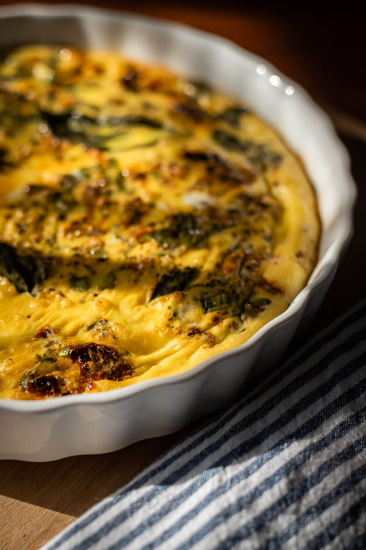 close up view of dairy free gluten free crustless quiche with tomatoes and basil