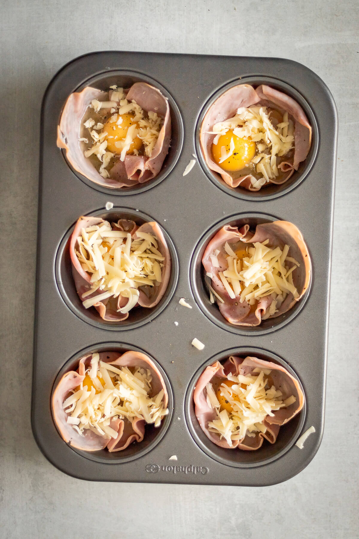 Ham and Egg Cups with Shredded Cheese in a muffin tin