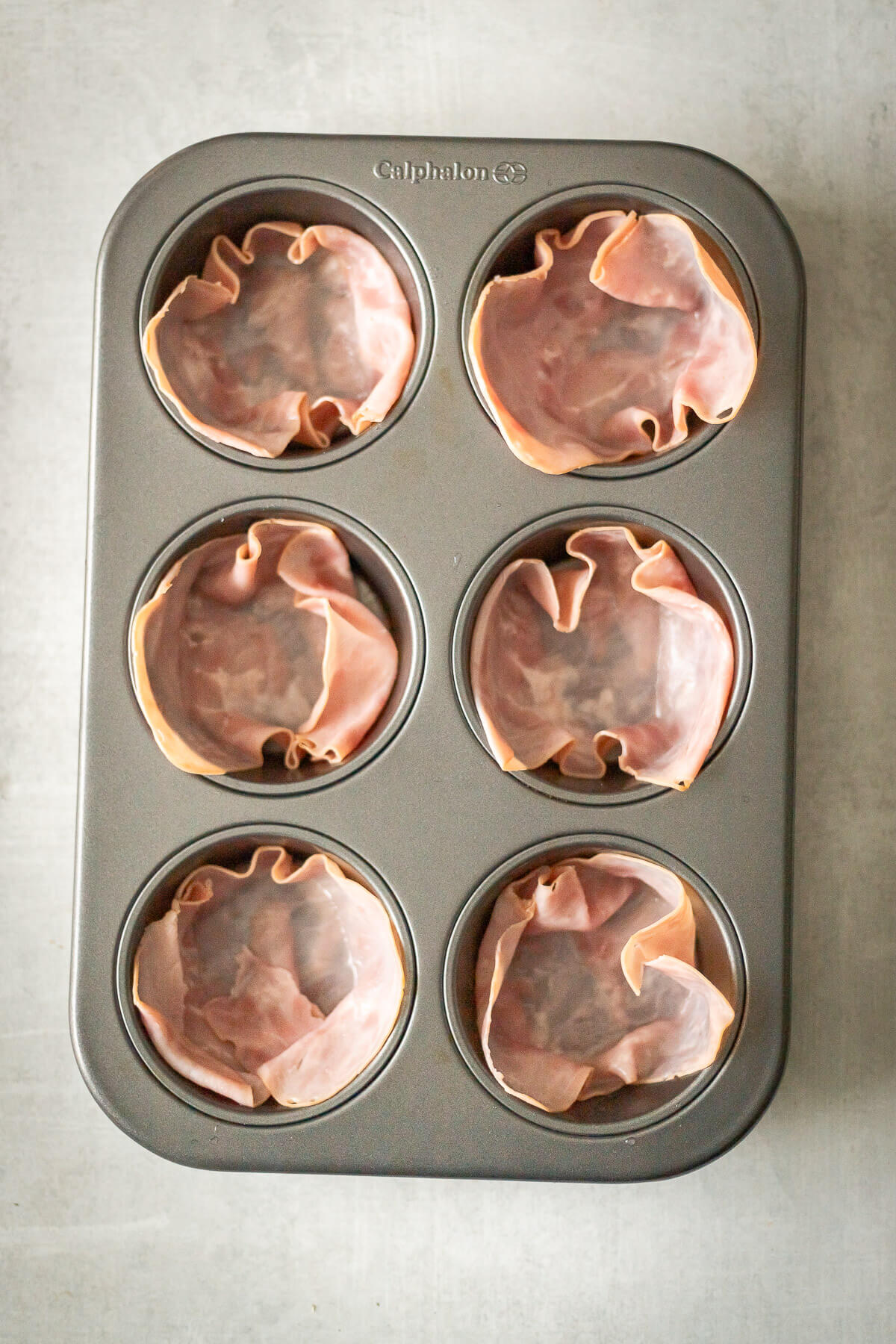 Layering Ham in muffin cups for ham and egg cups