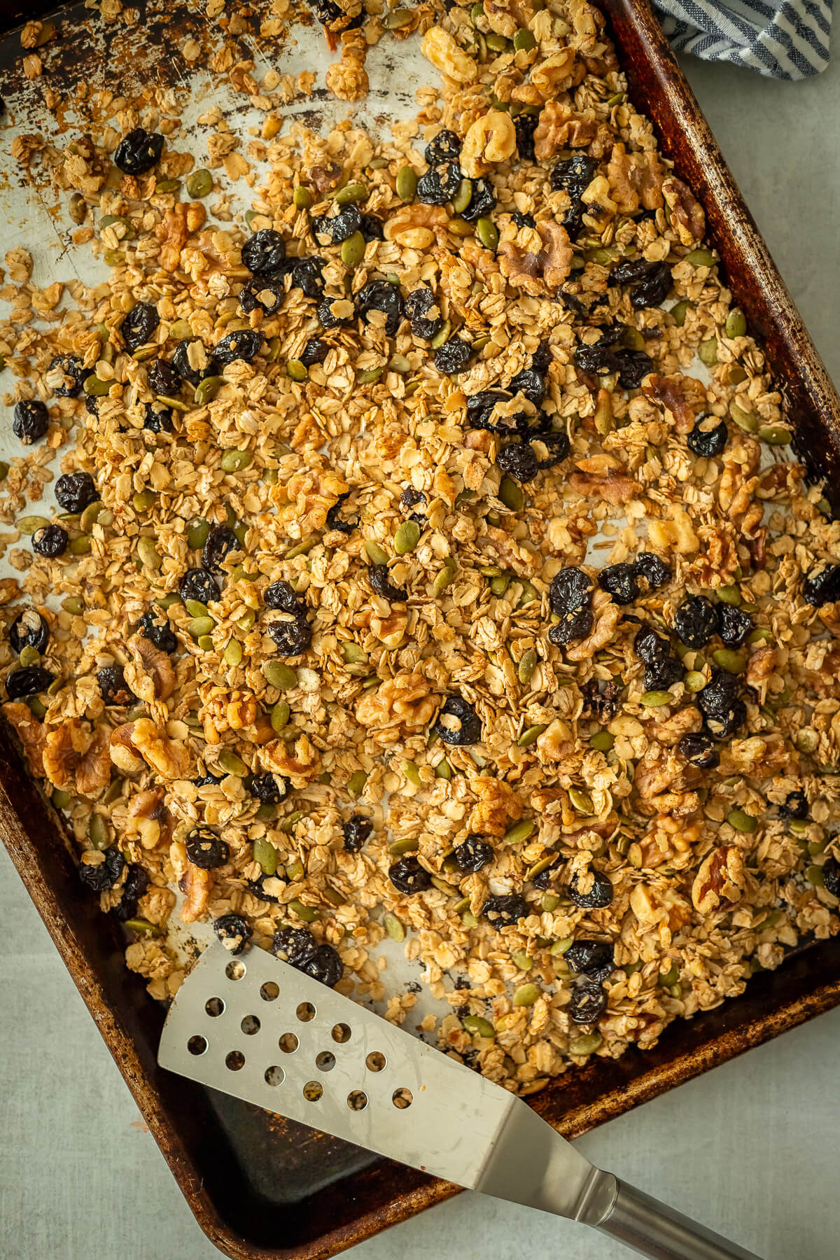 cherry walnut granola on a sheet pan with a spatula