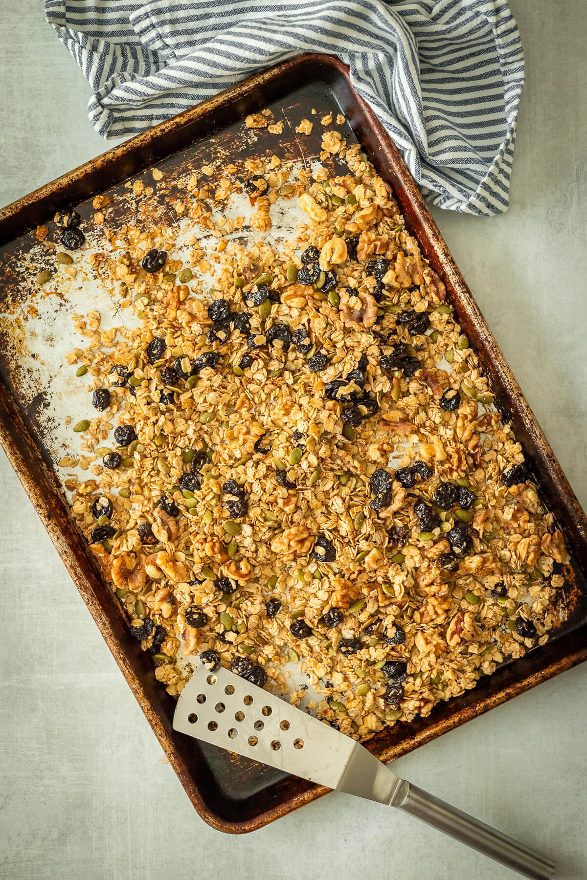 cherry walnut granola on a sheet pan with a spatula